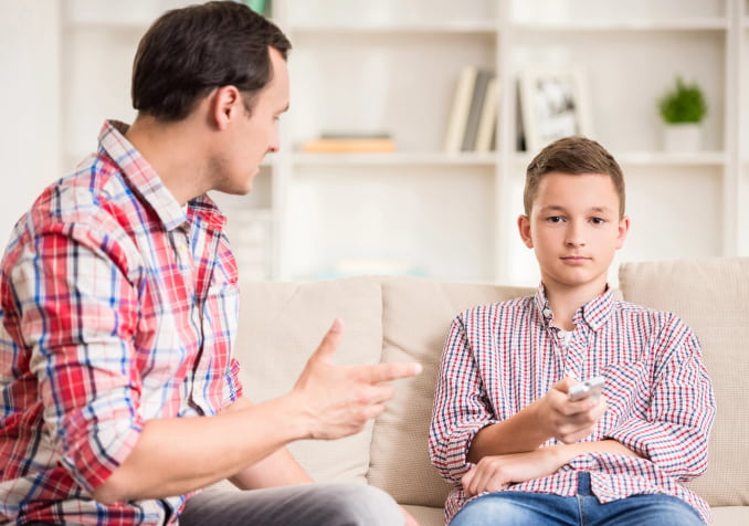 Dad talking to a son while watching Television