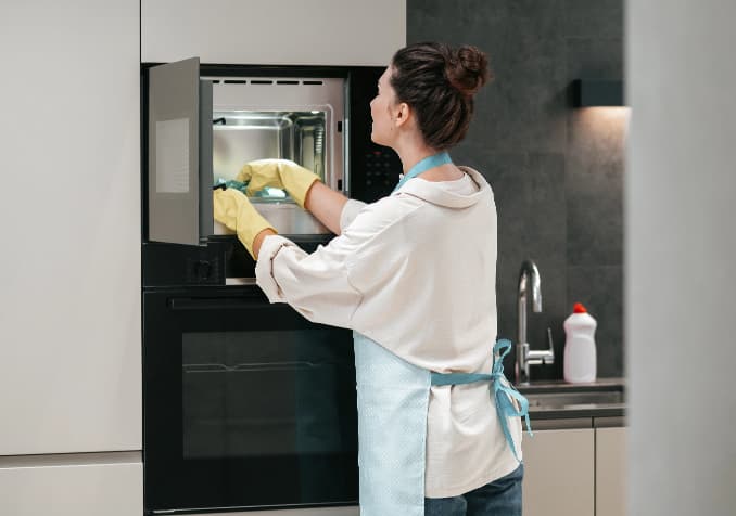 A Woman Cleaning Oven