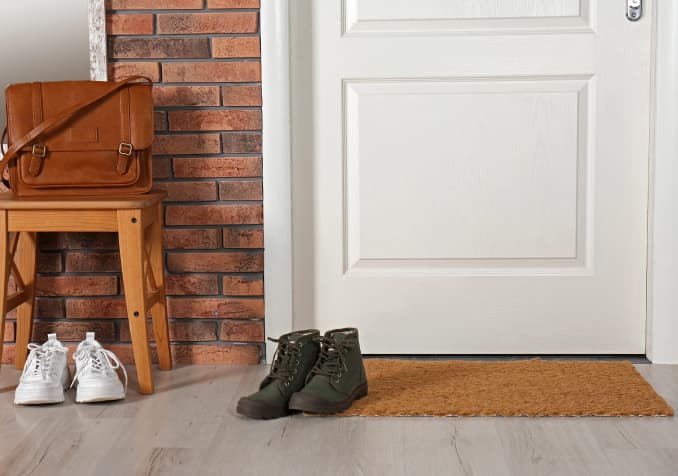 Brown Leather Bag with white rubber shoes and dark green shoes in front of the white door