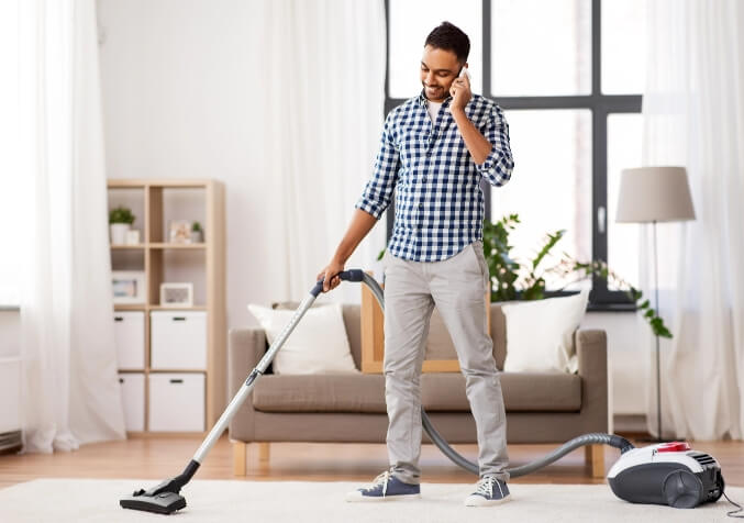 Man on Phone While Vacuuming the floor