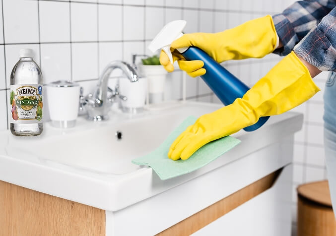 A Woman Cleaning Bathroom Sink using White Vinegar