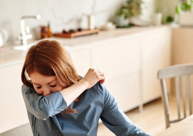 Woman Sneezing Into Her Elbow