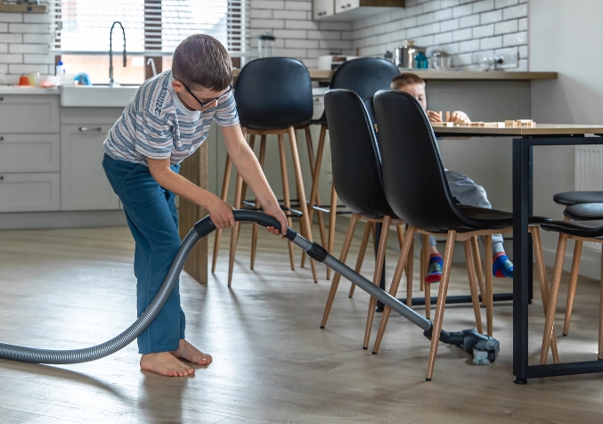 Young Boy Vacuuming Undernearth table