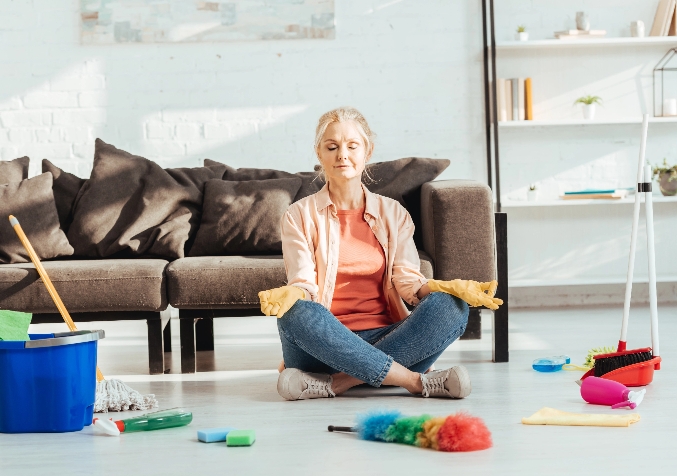Person sitting in the floor of living room while cleaning tools are scattered in the floor