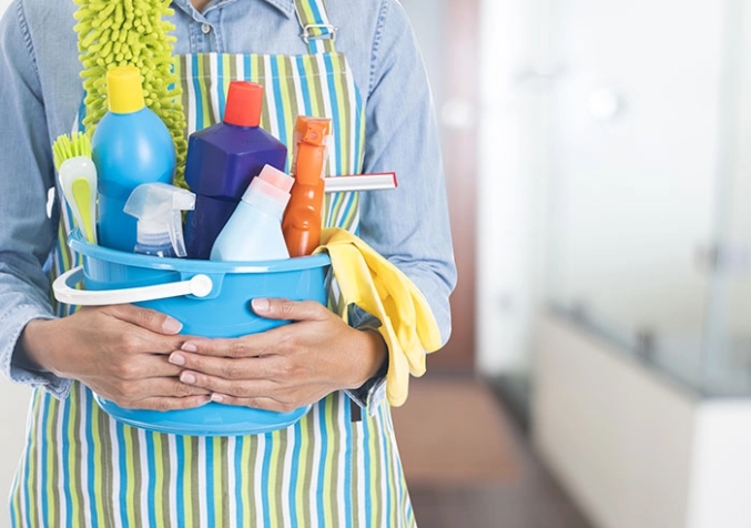 Person Holding Close a Pail Filled with Cleaning Products