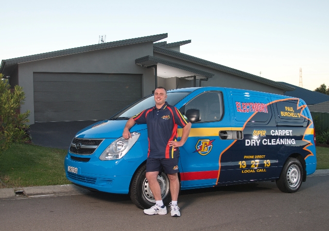 Electrodry Technician Standing Outside a House next to Company Van