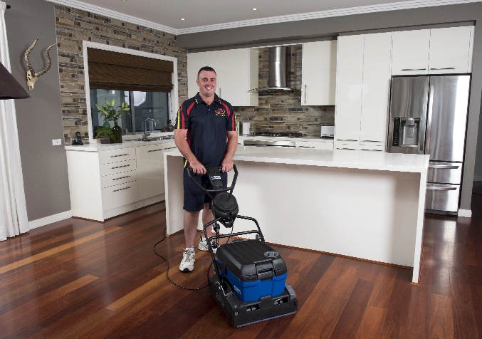 Electrodry Technician Standing with his Wood Sanding Equipment in Kitchen with Wooden Floors