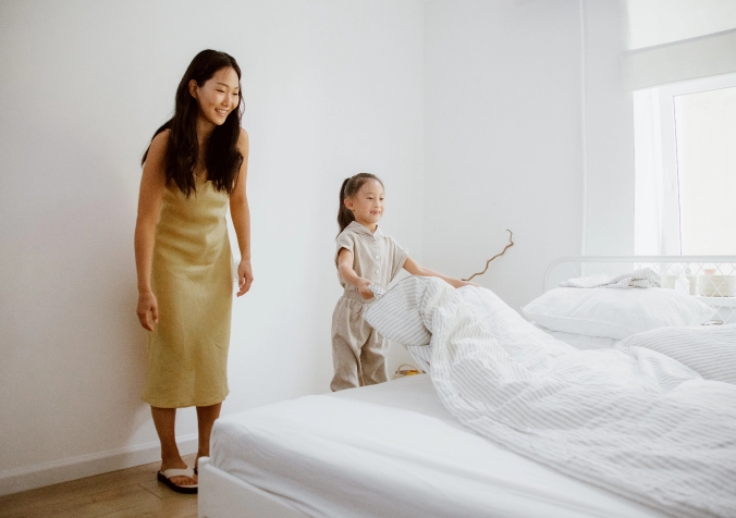 Mom and Little girl folding the bedsheets